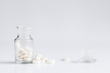 pills in glass jar on white background