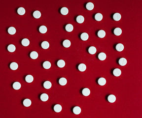 white pills on red background top view