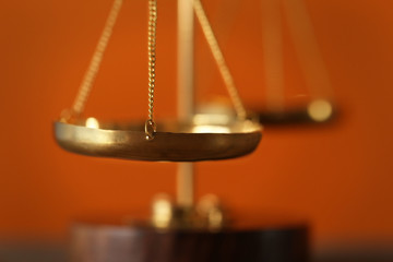 Justice scales on blurred orange background, closeup