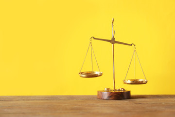 Justice scales on wooden table and  yellow background