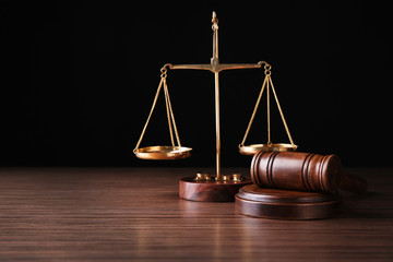 Justice scales and judges gavel on wooden table and black background