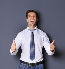 Young happy businessman on grey background