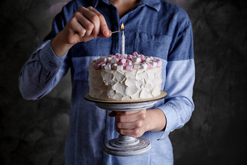 Woman lighting candle on cake with marshmallows