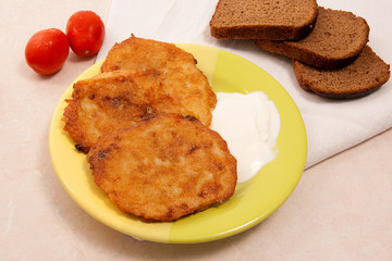 Potato pancakes with meat and tomatoes on green plate with rye b