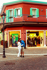 Hugging couple stands before the red house on the corner