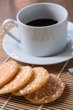 Black coffee in white cup and Crispy Rice Crackers with on woode