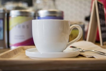 a white cup of coffee on wooden tray