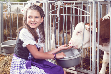 Dirndl füttert lächelnd ein junges Kälbchen
