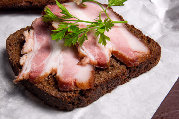 Slices of smoked bacon with rye black bread on the white packagi