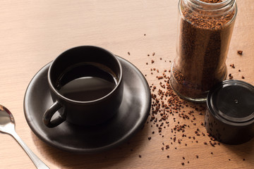 Black coffee in brown cup and roasted coffee on wooden table bac