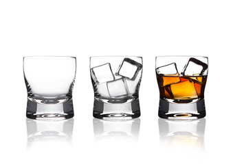 Glasss of whiskey with ice cubes with reflection