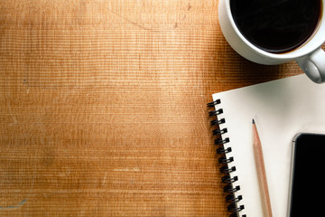 Top view of notebook, pencil, smartphone and coffee on wood back