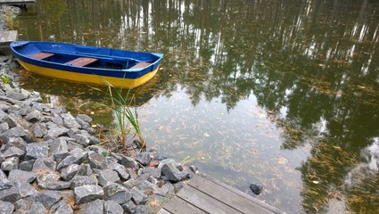 лодка на озере с отражением деревьев в воде © zelinskaalla