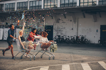 Multiethnic young people racing with shopping trolleys