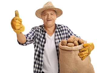 Fototapeta premium Elderly farmer holding a burlap sack and giving a thumb up