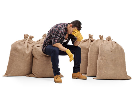 Depressed Farmer Sitting On A Burlap Sack