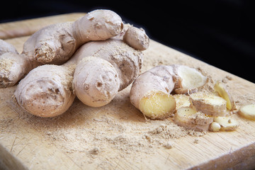 Close up of different forms of ginger against a wood worktop