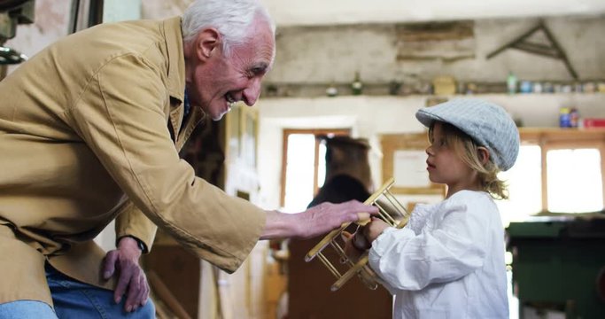  in an old carpentry shop a child and grandfather playing with a wooden airplane concept of tradition that continues over time