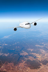 Fototapeta na wymiar Podróż samolotem, samolot lecący w błękitnym niebie wysoko nad ziemią