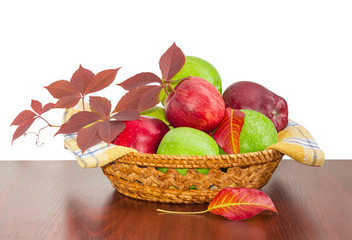 Red and green apples on checkered napkin in wicker basket