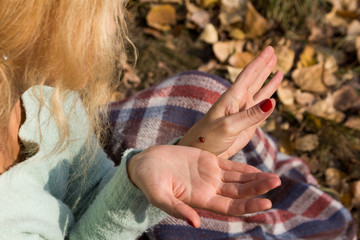 Fototapeta premium Girl sitting on the grass and sees a ladybird.
