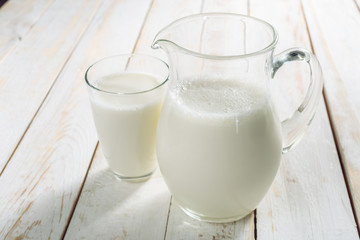 fresh milk in glass jug and glass on wooden background