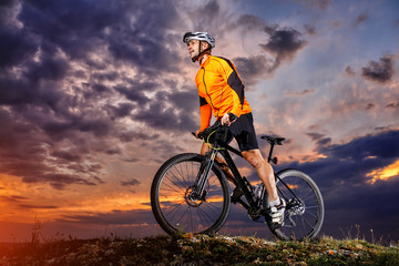 Fototapeta na wymiar Man in helmet stay on bicycle under sky with clouds.