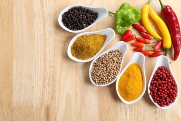 Aromatic and colorful spices in ceramic containers on a wooden background.