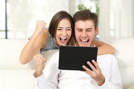 Excited couple winning online with tablet