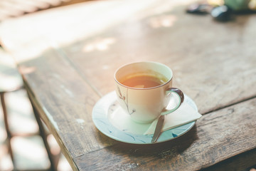 Cup of coffee on wooden table. Photo in old color image style.