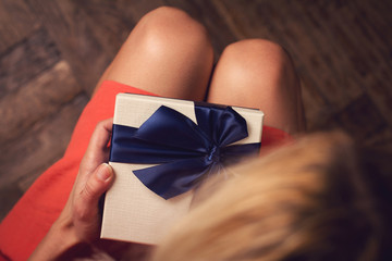  Woman opening a cardboard gift box with blue ribbon
