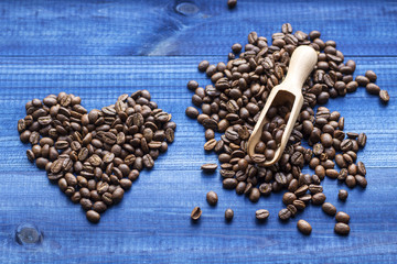Heart made of coffee beans with wooden spoon on blue wooden background