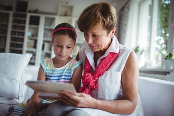 Senior woman and her granddaughter looking at a photo album
