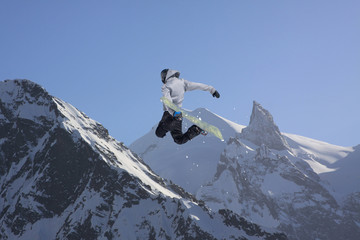 Snowboarder jumping on mountains. Extreme snowboard freeride sport.
