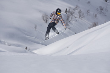 Fototapeta na wymiar Snowboarder jumping on mountains. Extreme snowboard freeride sport.