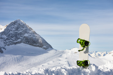 Snowboard in snow slope on a beautiful mountain background