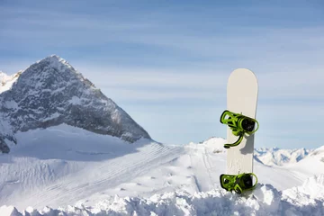Poster Snowboard in snow slope on a beautiful mountain background © kobeza