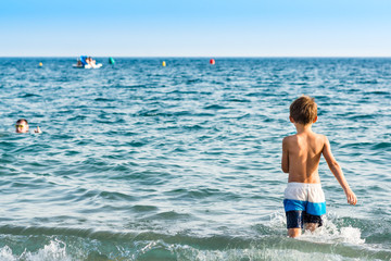 A kid plays with the waves at a mediterranean beach in Granada, Spain