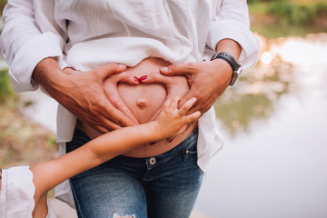 A family of hands form a heart - father on the outside, then mother's hands and infant baby hands in the middle.