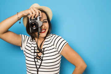 Fashion young girl makes the photo with old camera. Blue backgro