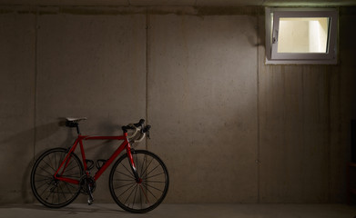 Fototapeta na wymiar Single red bike leaning on wall in garage