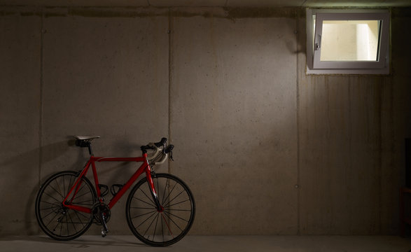 Single red bike leaning on wall in garage