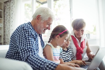 Grandchildren using laptop with their grandparents