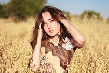 Portrait of a beautiful young woman with green eyes in a wheat field. She was makeup and body paint. The landscape has a lovely colorful.  © pablobenii