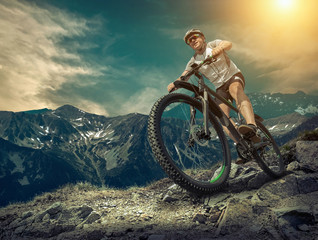 Fototapeta premium Man in helmet and glasses stay on the bicycle under sky with clo