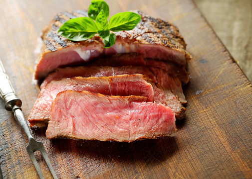 slices of grilled steak on a wooden background