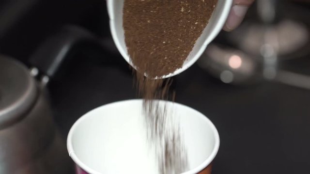 ground coffee is poured from one container to another