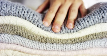 A hand touching a pile of colorful wool sweaters warm fluffy soft and comfortable to wear. cleaning concept, softness, warmth, cashmere, whiteness. - Powered by Adobe