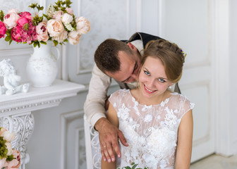 Charming bride and groom in their bedroom. Gentle kiss.