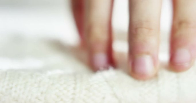 A hand touching a pile of colorful wool sweaters warm fluffy soft and comfortable to wear. cleaning concept, softness, warmth, cashmere, whiteness.